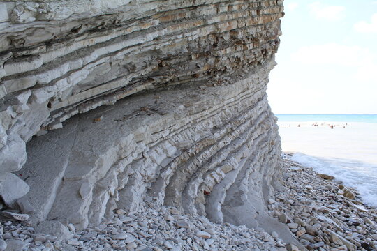 Layered rock formation along the beach with ocean in background  