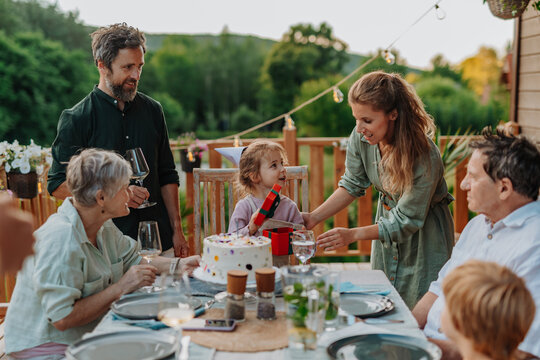 Multi generation family grilling outside on patio in summer during garden party