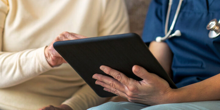 Healthcare technology for the elderly with medical staff checking medical information with an older person on a tablet