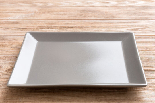Perspective view of empty square plate on wooden background. Empty space for your design