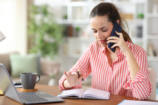 Disgusted teleworker checking calendar talking on phone