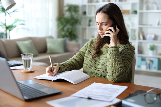 Annoyed teleworker talking on phone and checking agenda