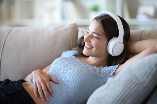 Happy teenage girl listening to music from headphone and relaxing