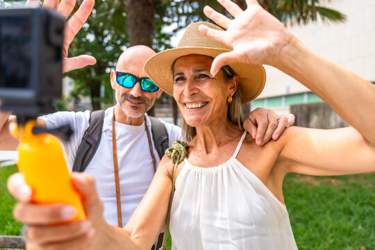Middle aged couple recording summer travel vlog with action camera