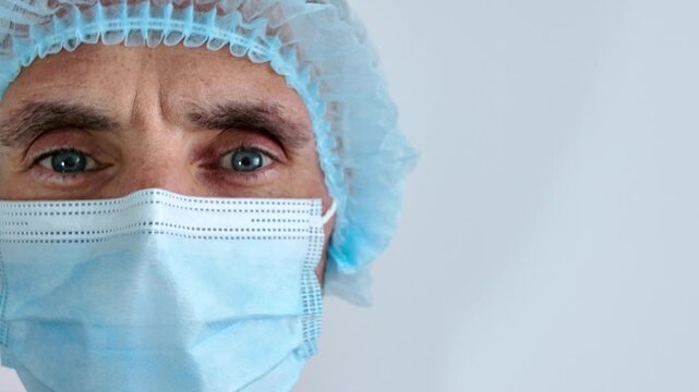 Close-up of the face of a male surgeon looking at the camera with a kind and supportive look