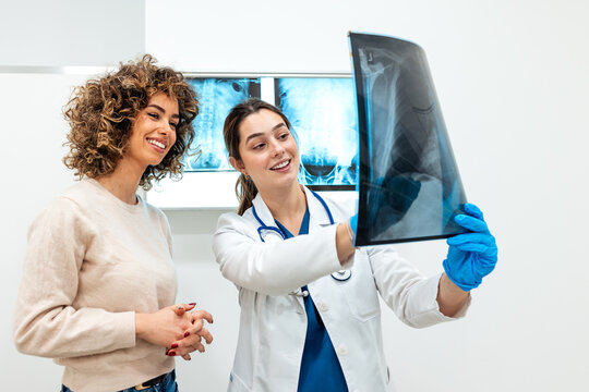 Doctor showing X-ray to patient in clinic. Professional female doctor explaining medical results to woman. Healthcare and medicine. Smiling patient listening to doctor about diagnosis in office.