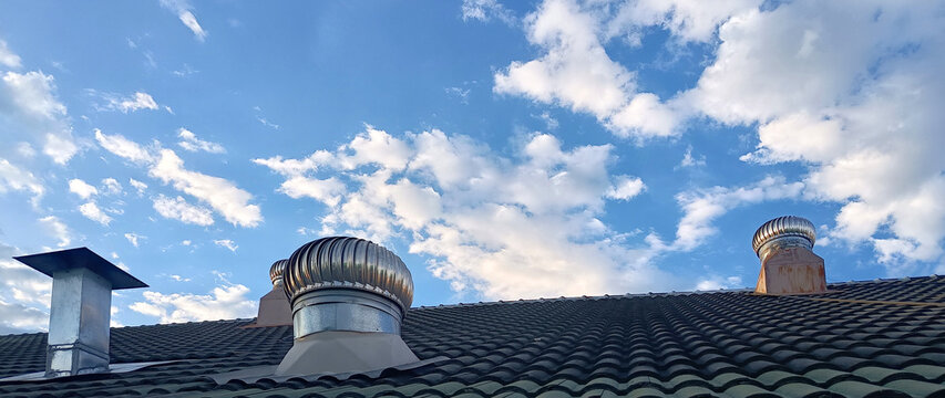 Stainless steel roof ventilator spin on tile roof with blue sky. Roof exhaust ventilation fan ball on factory or house roof, Air ventilator mechanism installed. not ai