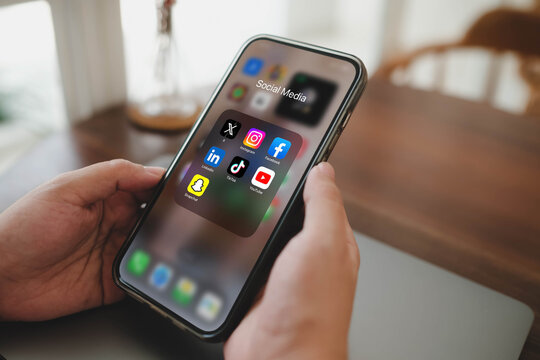 Bangkok, Thailand. July 22, 2026; A close-up view of a person's hands holding a smartphone displaying a social media application folder filled with popular brand icons.