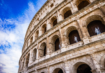 Naklejka premium Colosseum arches and sculptures under blue sky, Rome