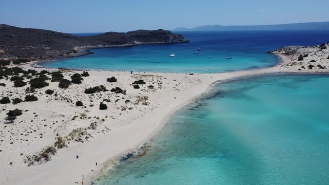 Drone footage of Simos Beach on Elafonisos Island, Greece, featuring white sand dunes, turquoise lagoons, crystal-clear Mediterranean waters, and an iconic coastal landscape.