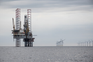 North Sea oil rig drilling platform. maritime sea offshore industry fossil fuel natural resource extraction Competing energy power sources next to new clean renewable wind turbines © drew