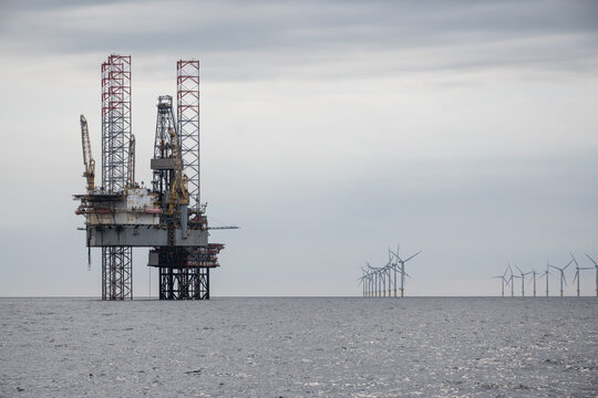 North Sea oil rig drilling platform. maritime sea offshore industry fossil fuel natural resource extraction Competing energy power sources next to new clean renewable wind turbines