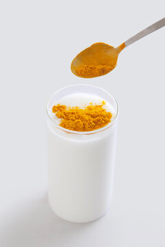 Pouring turmeric powder into glass of milk