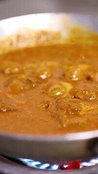 Spicy Indian Curry Simmering in Stainless Steel Pan in Bangkok Kitchen