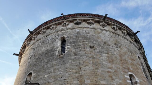 Low-angle perspective of the round tower at Ch&acirc;teau d'Amboise, highlighting its imposing fortifications, narrow windows and historic limestone masonry.