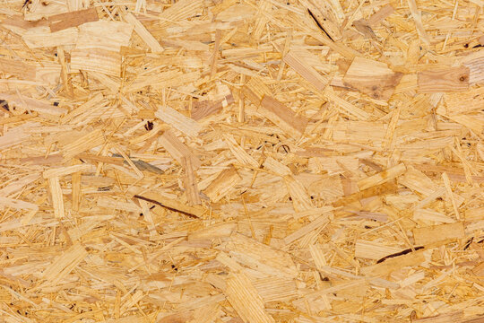 The scene presents a detailed close up view of an oriented strand board surface showcasing compressed wood flakes and natural timber textures.