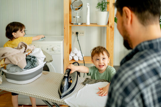 Father with son ironing clothes at home