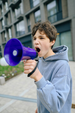 Teenage boy shouts into a purple loudspeaker during a city rally
