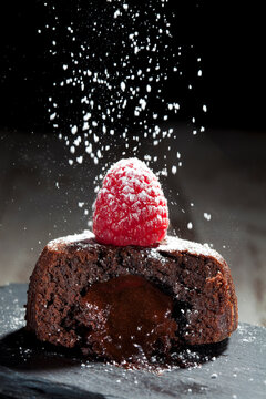 Sliced small chocolate tart with melted chocolate filling garnished with raspberry