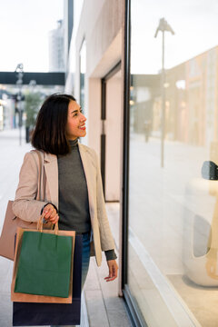 Happy young woman shopping and holding paper bags outdoors