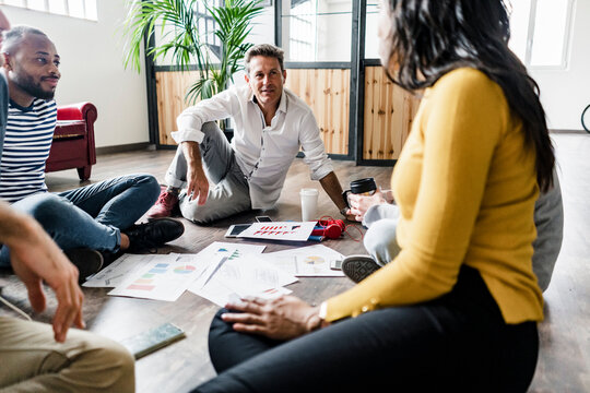 Business team sitting on floor discussing documents in loft office