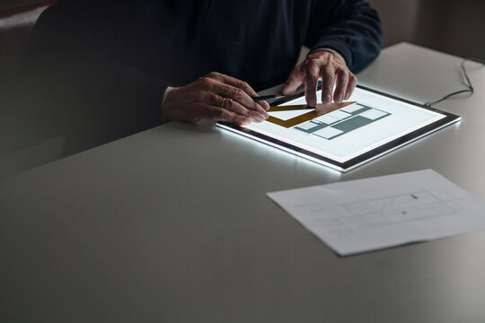 Close-up of senior man using tablet with architectural plan