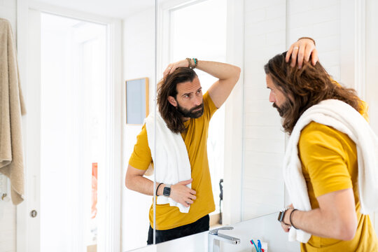 Man with head in hand looking at mirror