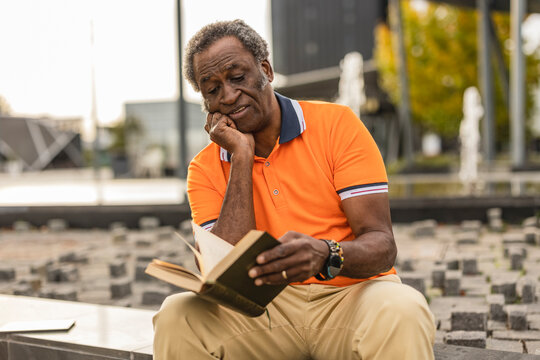 Senior man with hand on chin reading book