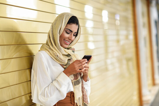 Spain, Granada, young Arab tourist woman wearing hijab, using smartphone