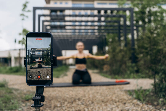 Smartphone records a woman exercising with a resistance band outdoors