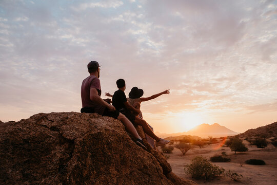 Namibia, Spitzkoppe, friends sitting on a rock watching the sunset