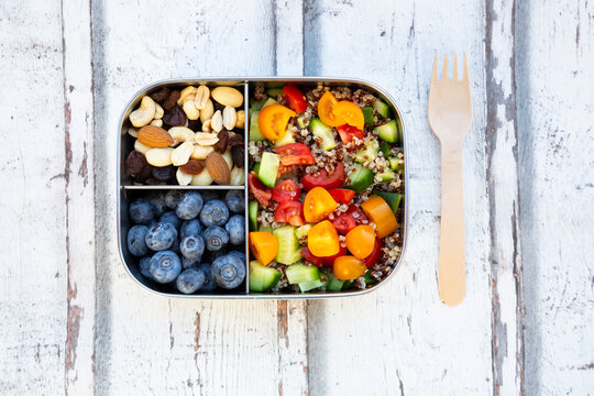 Lunchbox with quinoa salad with tomato and cucumber, blue berry and trail mix