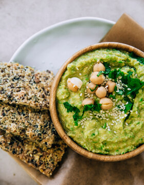 Peas hummus in wooden bowl, crispbread on plate