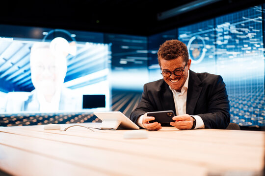 Smiling businessman watches a video on his smartphone in a TV studio