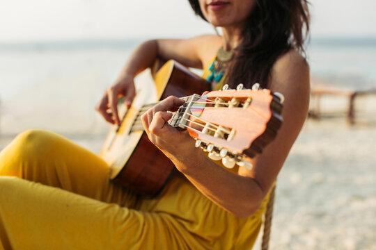 Thailand, Koh Phangan, woman playing guitar at the beach