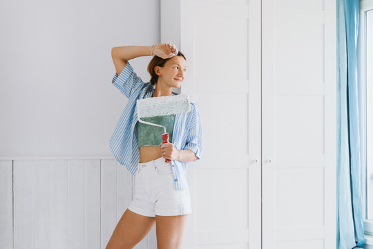 Smiling woman holds a paint roller during home renovation indoors