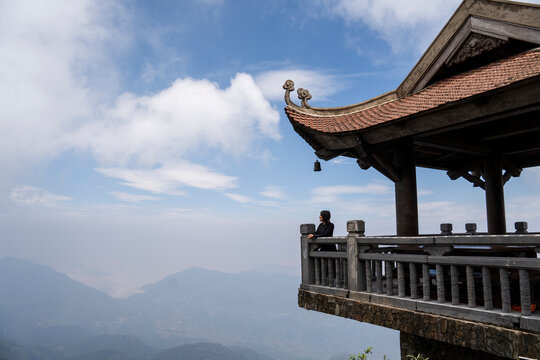 Woman admires mountain view from temple balcony in Sapa Vietnam