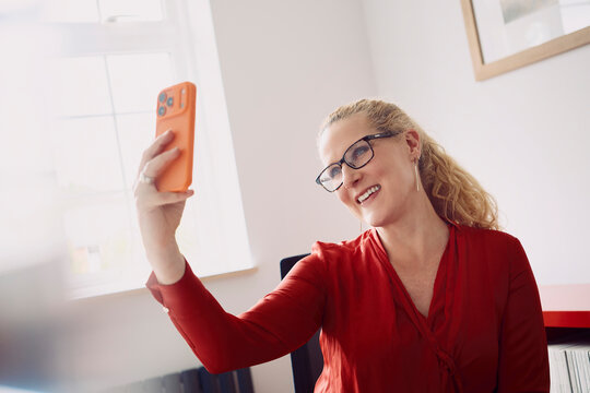 Happy woman in red blouse has a video call at the home office