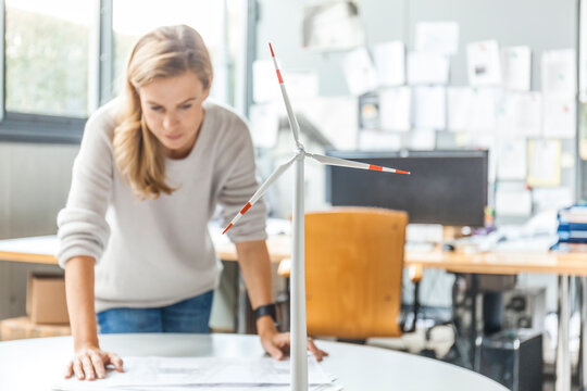 Woman in office working on plan with wind turbine model on table