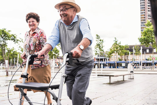 Senior man using wheeled walker for running away from his wife