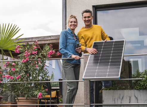 Couple installing solar panel on balcony