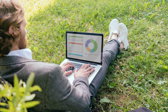 Young entrepreneur analyzing data on laptop while sitting at downtown