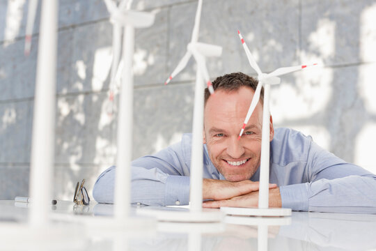 Smiling businessman with wind turbine models at a trade fair desk