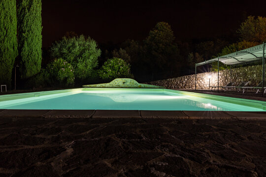 Illuminated swimming pool on the Montemassi hillside surrounded by cypresses and oleanders n the province of Grosseto. Italy