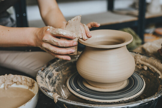 Hands of potter molding pot on pottery wheel at workshop