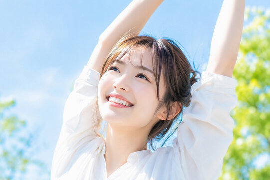 休日の朝、晴れの日に気持ちよさそうに背伸びをする若い日本人女性