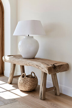 Weathered driftwood console table with ceramic lamp and woven basket in a modern coastal entryway with soft afternoon light
