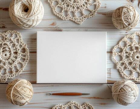 Blank white canvas mockup surrounded by crochet doilies and yarn balls on wooden background