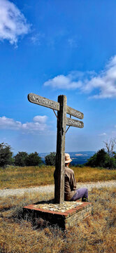 Walker Resting Beside Ancient Signpost on Bignor Hill Along the South Downs Way, West Sussex.