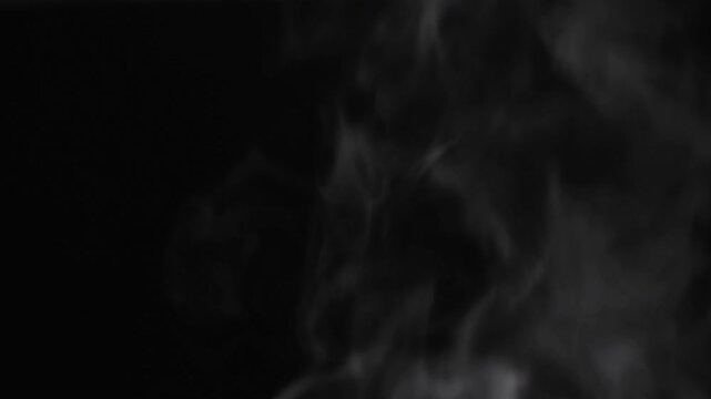 Abstract white steam or smoke rising against black background in static shot
